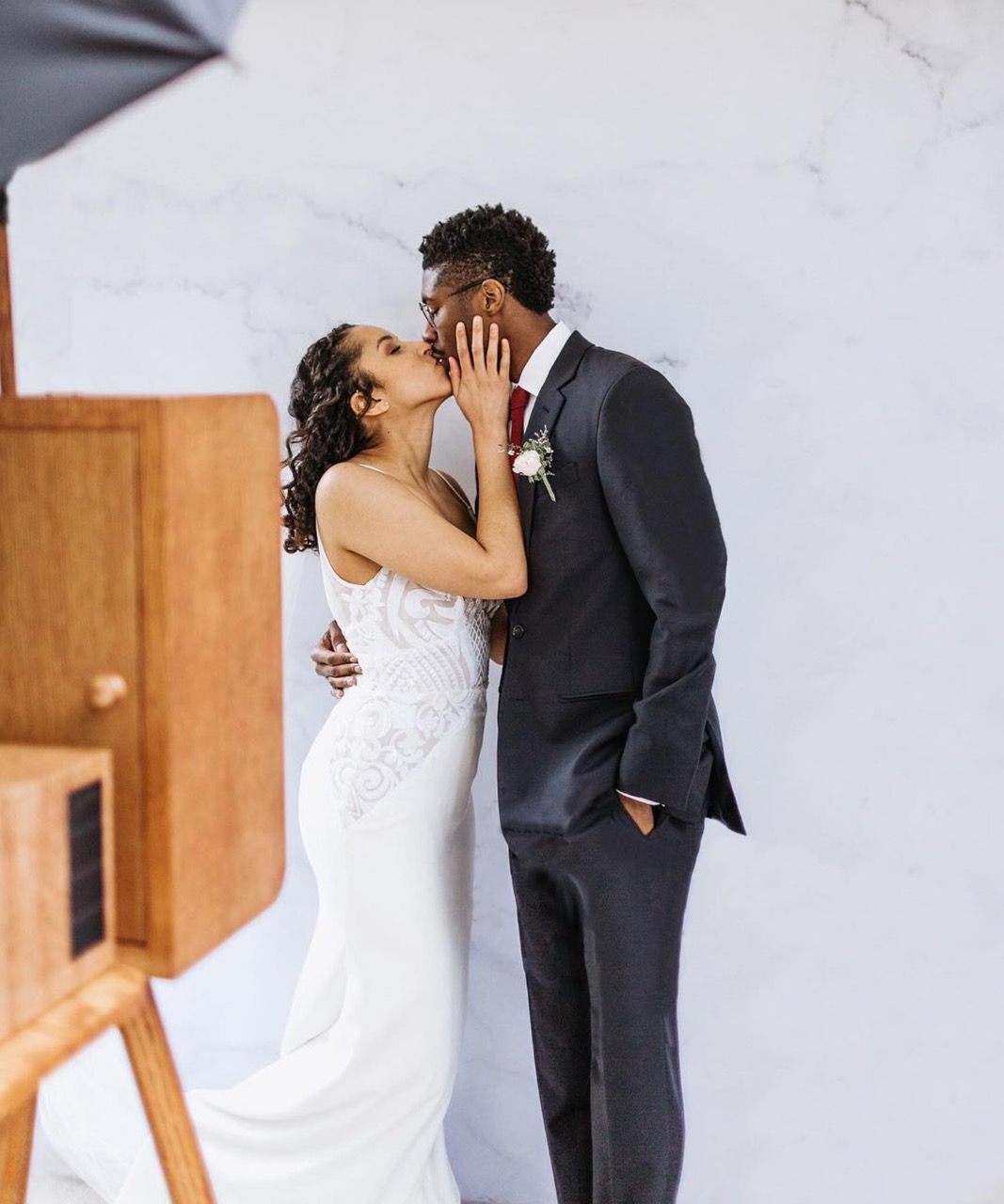 Bride and groom kissing beside TBD's handmade walnut photo booth